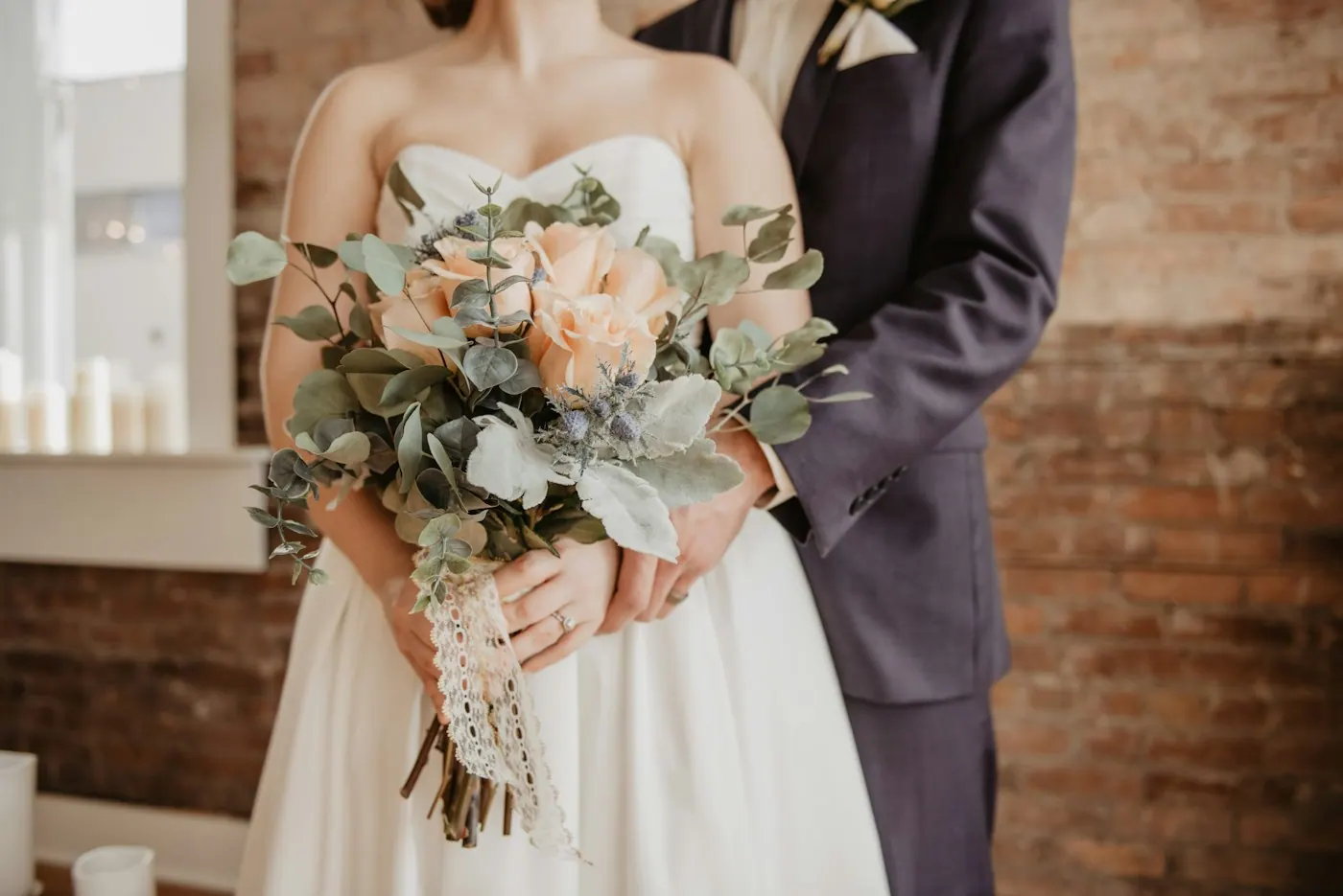 Braut mit Pfirsichrosen-Bouquet vor warmem Holzinterieur